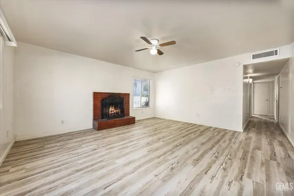 a view of empty room with wooden floor and ceiling fan