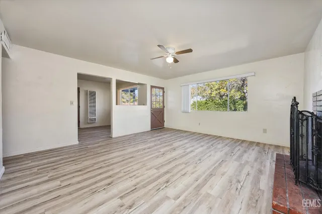 a view of an empty room with a window and wooden floor