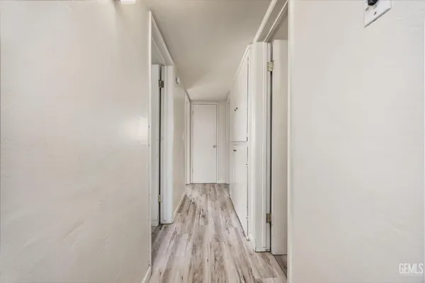 a view of a hallway with wooden floor and a bathroom