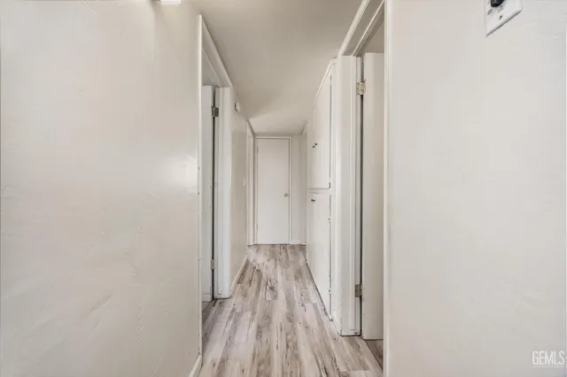a view of a hallway with wooden floor and a bathroom
