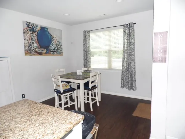 a dining room with wooden floor and a floor to ceiling window