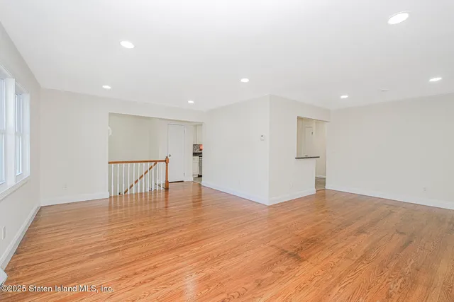 a view of empty room with wooden floor and windows
