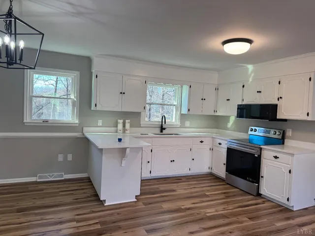 a kitchen with kitchen island granite countertop a sink cabinets and wooden floor