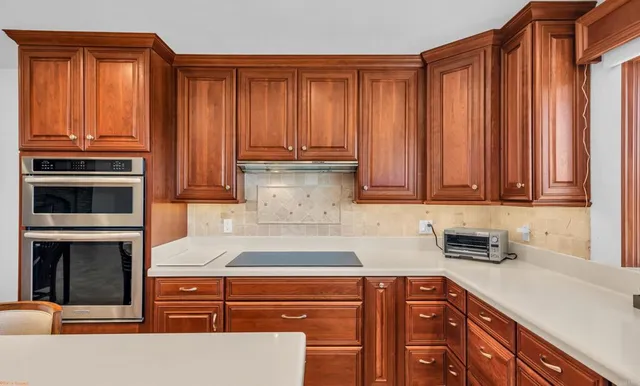 a kitchen with stainless steel appliances granite countertop a sink a stove and a wooden cabinets