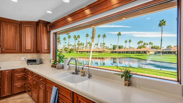 a room with stainless steel appliances kitchen island granite countertop a refrigerator a stove and a sink with dishwasher