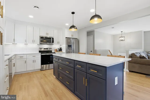 a kitchen with kitchen island granite countertop a stove a sink a center island and cabinets