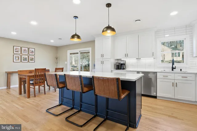 a kitchen with stainless steel appliances granite countertop a stove a sink a dining table and chairs with wooden floor