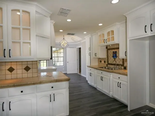 a large kitchen with granite countertop a large stove a sink and white cabinets