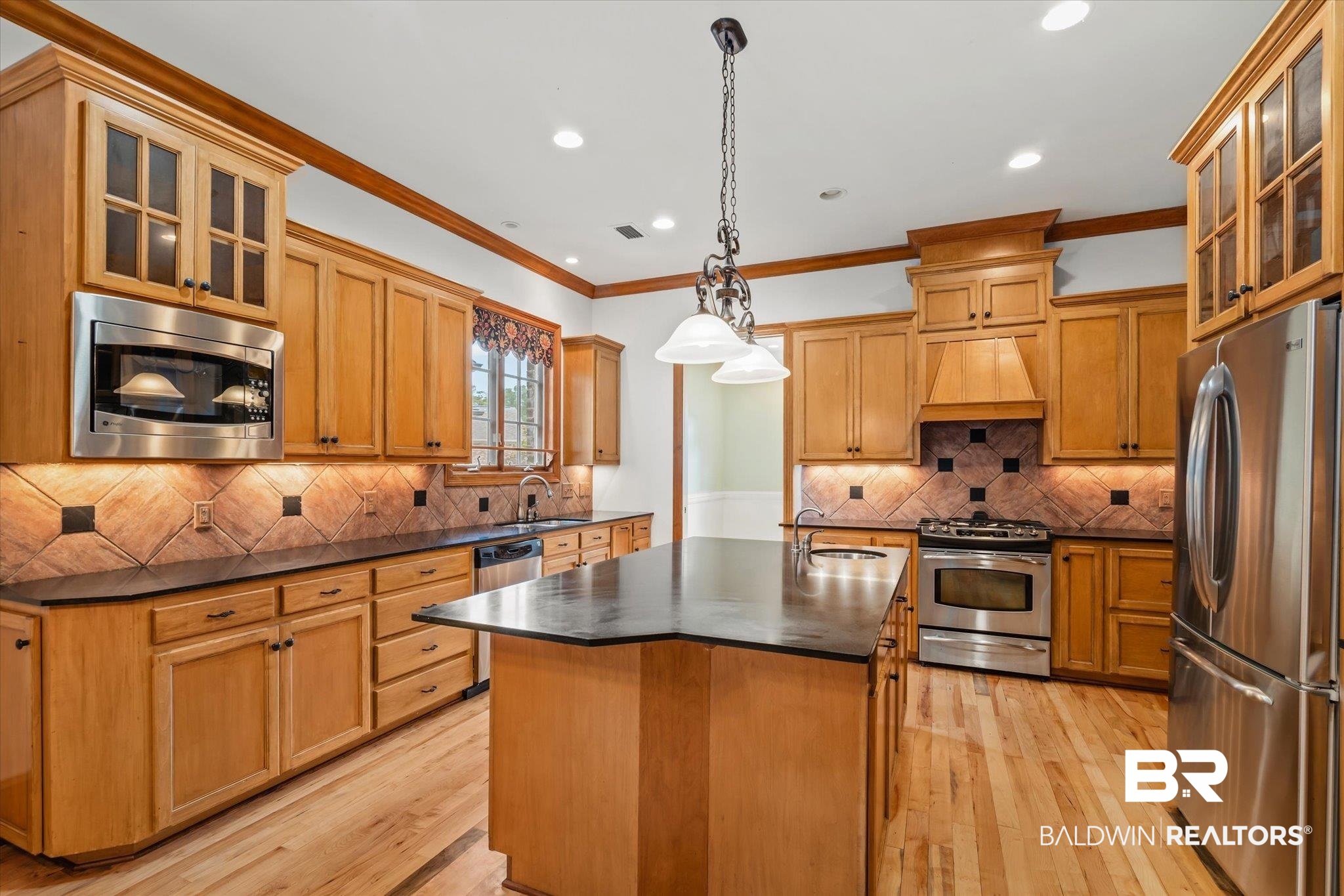 812 Country Club Court Mobile, AL 36609 - Photo 5 of 34 Kitchen featuring tasteful backsplash, stainless steel appliances, an island with sink, sink, and hanging light fixtures