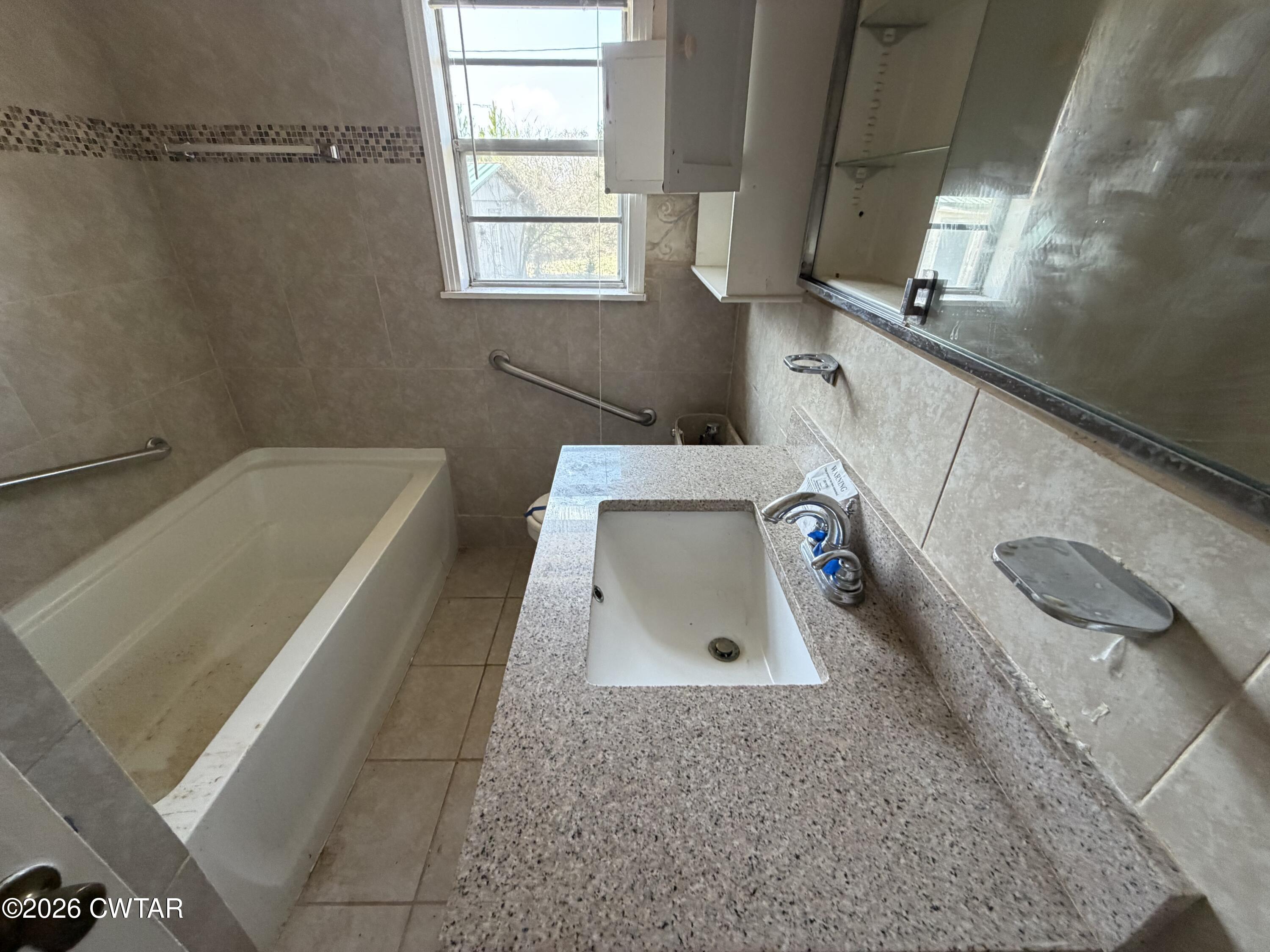 13835 Old Jackson Road Whiteville, TN 38075 - Photo 26 of 27 a bathroom with a tub sink and window