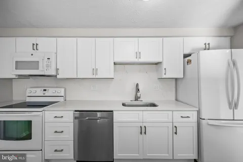 a kitchen with white cabinets and white appliances