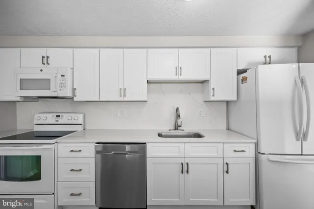 a kitchen with white cabinets and white appliances