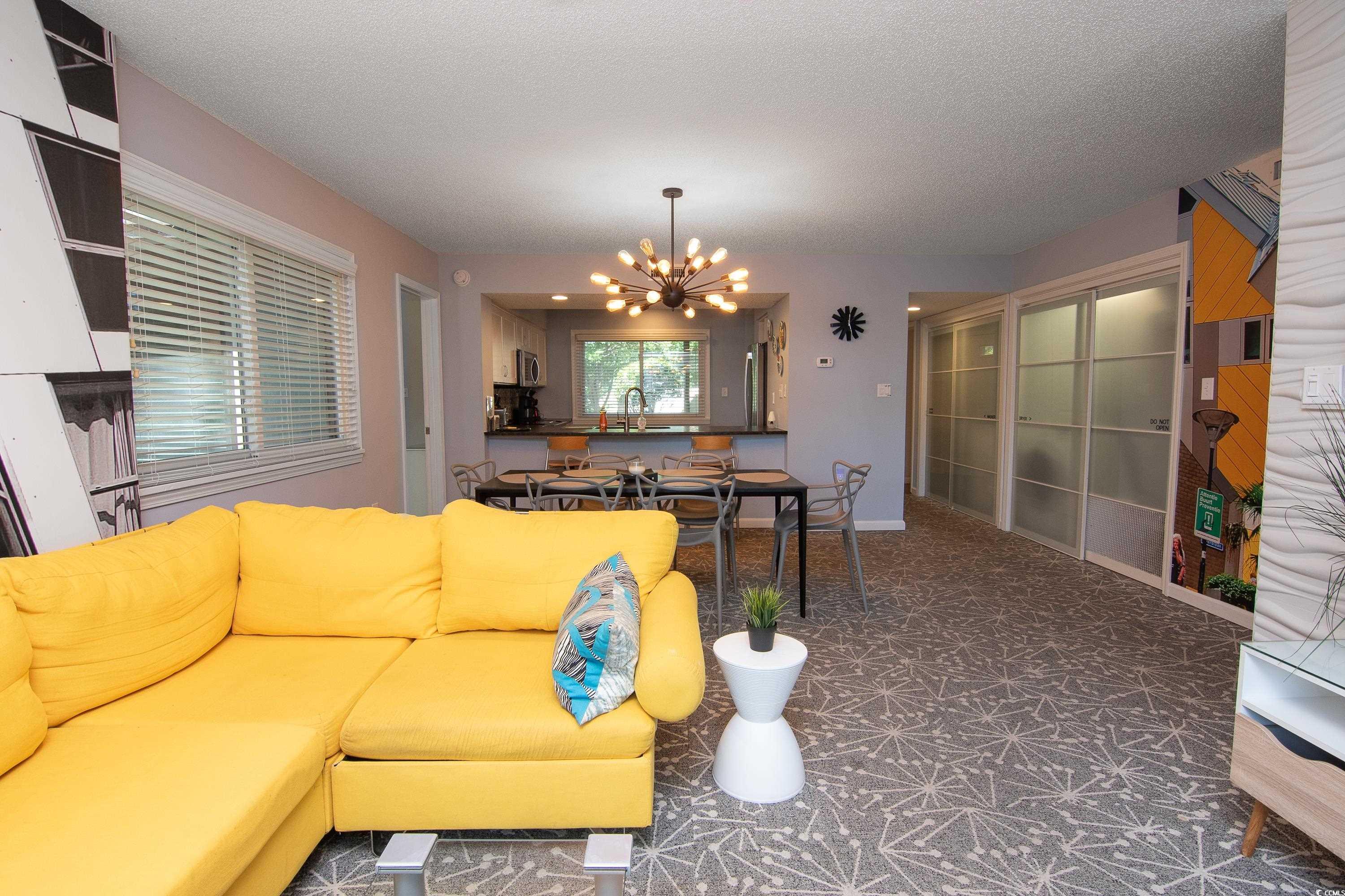211 Baslow Court, Unit 2C Myrtle Beach, SC 29572 - Photo 14 of 33 Living room with a chandelier, a textured ceiling, and carpet floors