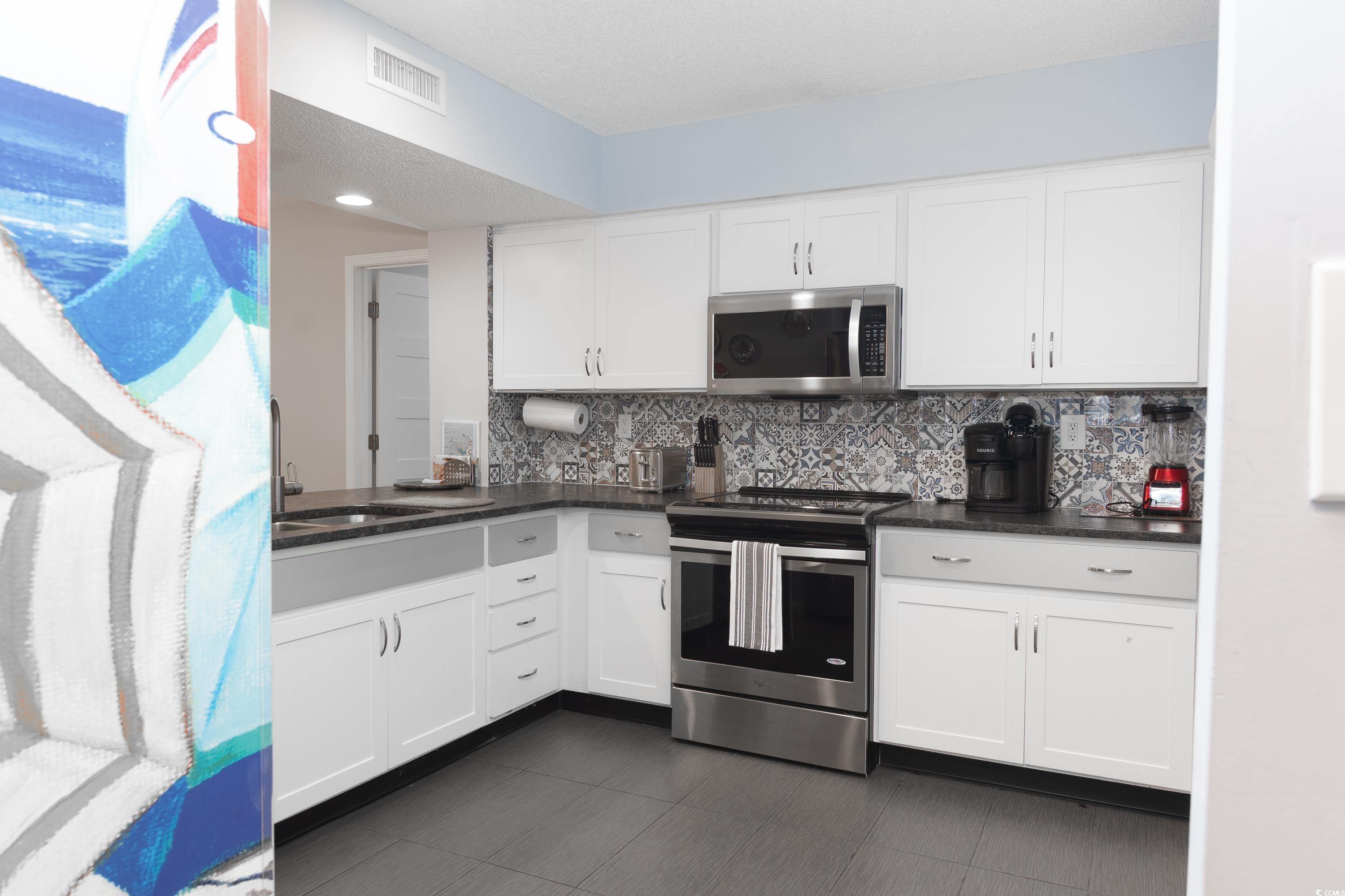 211 Baslow Court, Unit 2C Myrtle Beach, SC 29572 - Photo 3 of 33 Kitchen featuring stainless steel appliances, white cabinetry, backsplash, and dark stone countertops