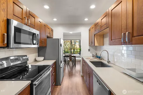 a kitchen with kitchen island granite countertop a stove a sink a refrigerator and cabinets
