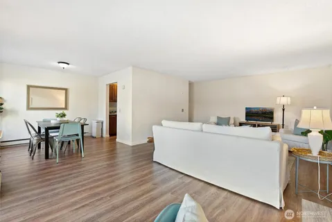 a living room with furniture and a dining table with wooden floor