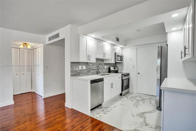 a kitchen with a refrigerator cabinets and wooden floor