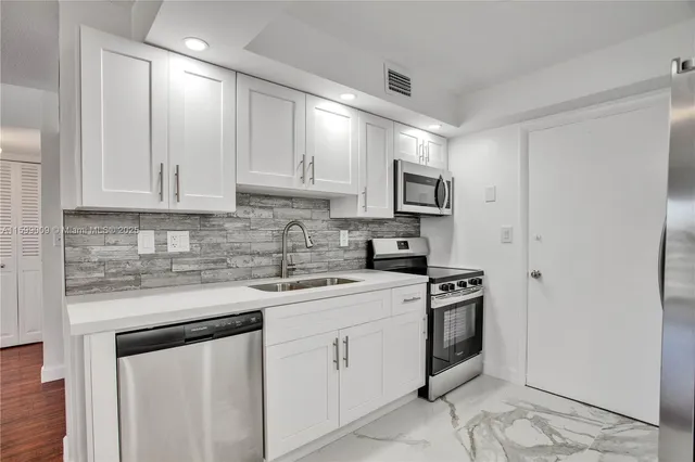 a kitchen with white cabinets sink and stainless steel appliances