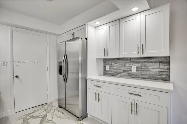 a kitchen with stainless steel appliances granite countertop a refrigerator and white cabinets