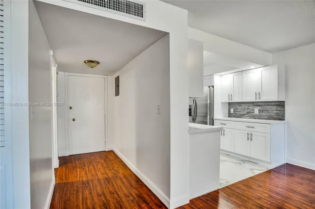 a kitchen with white cabinets and wooden floor