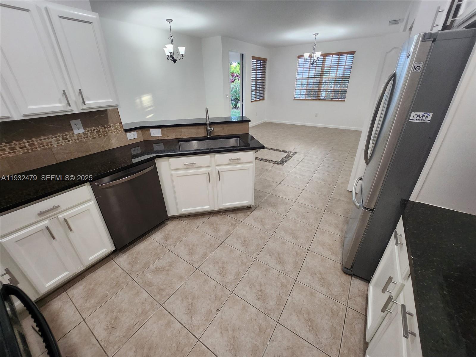 13973 Southwest 276th Way Homestead, FL 33032 - Photo 13 of 43 a kitchen with granite countertop white cabinets and black appliances