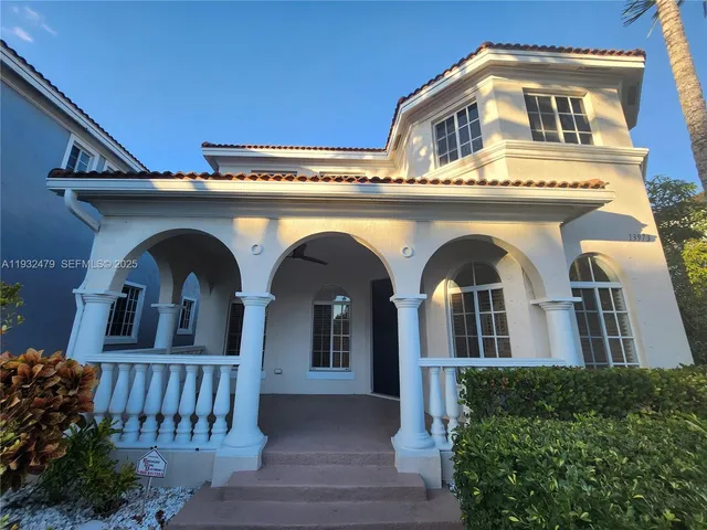 a view of a blue house with large windows and a small yard