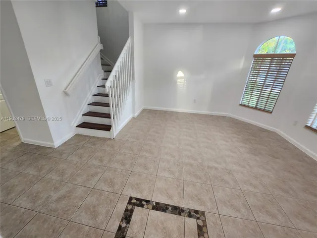 a view of an empty room with stairs and a window
