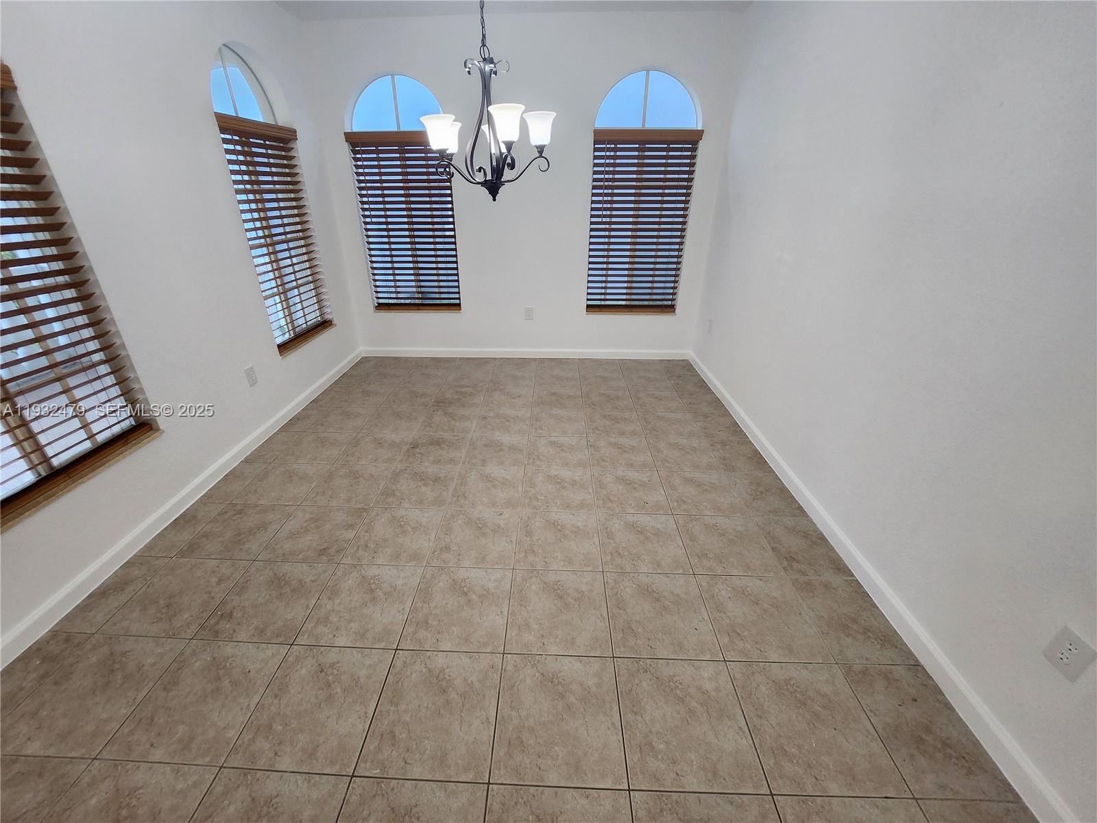 13973 Southwest 276th Way Homestead, FL 33032 - Photo 8 of 43 an empty room with kitchen view and a chandelier