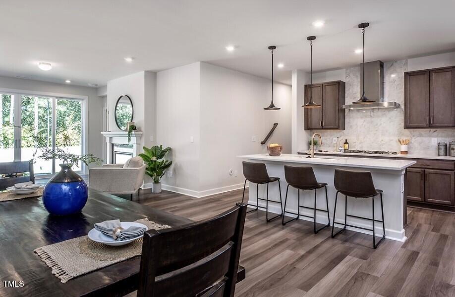 6103 Adecor Way Raleigh, NC 27617 - Photo 6 of 27 a kitchen with stainless steel appliances kitchen island granite countertop a stove a sink a dining table and chairs with wooden floor
