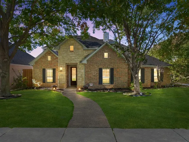 a front view of a house with a garden and trees