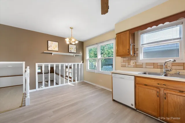 a kitchen with stainless steel appliances granite countertop a refrigerator a sink dishwasher and wooden cabinets with wooden floor