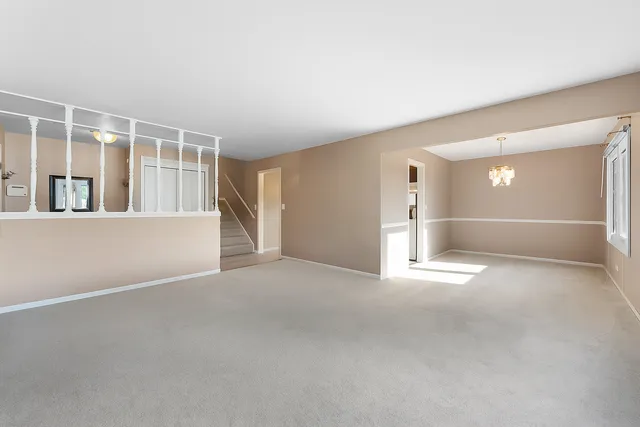 an empty room with chandelier fan and windows