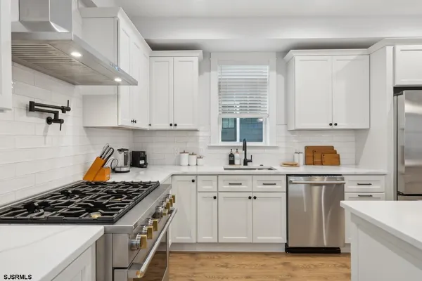a kitchen with stainless steel appliances a sink dishwasher stove and refrigerator