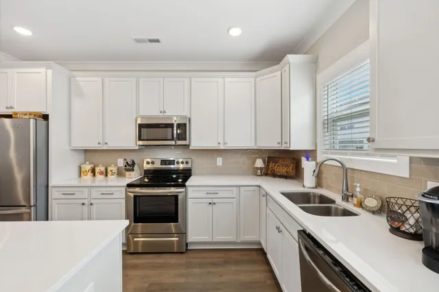 a kitchen with a sink white cabinets and white appliances