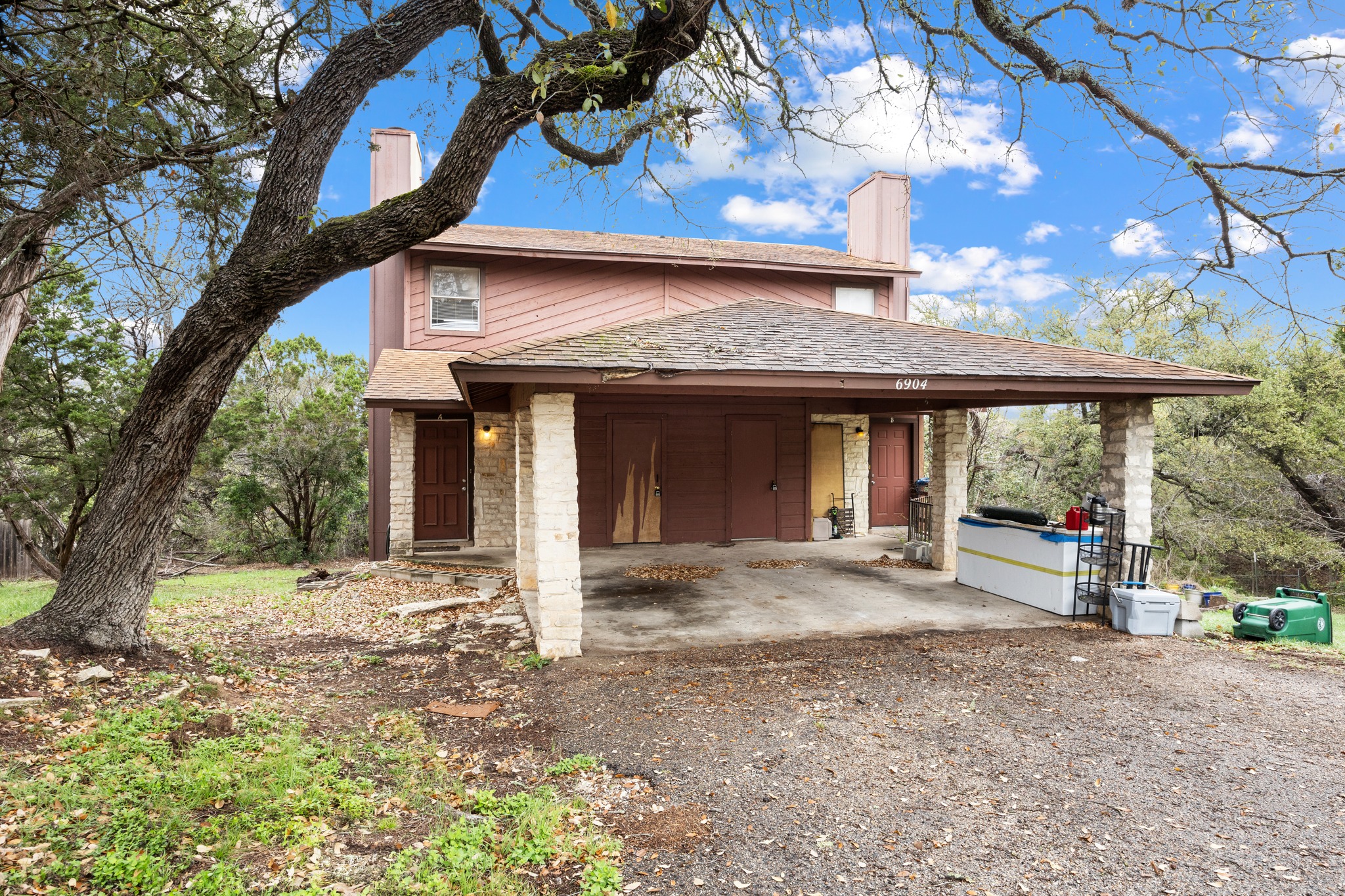 6904 Rifle Bend, Unit A Austin, TX 78736 - Photo 3 of 22 View of front of house featuring a chimney, a patio area, driveway, an attached carport, and roof with shingles