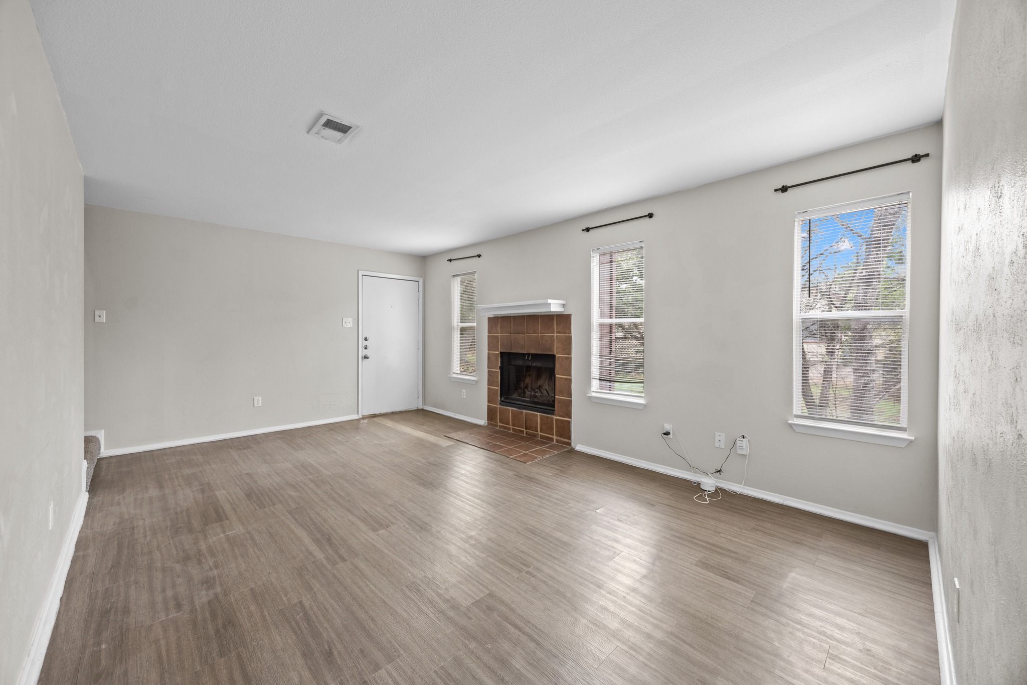 6904 Rifle Bend, Unit A Austin, TX 78736 - Photo 8 of 22 Unfurnished living room with wood finished floors and a fireplace