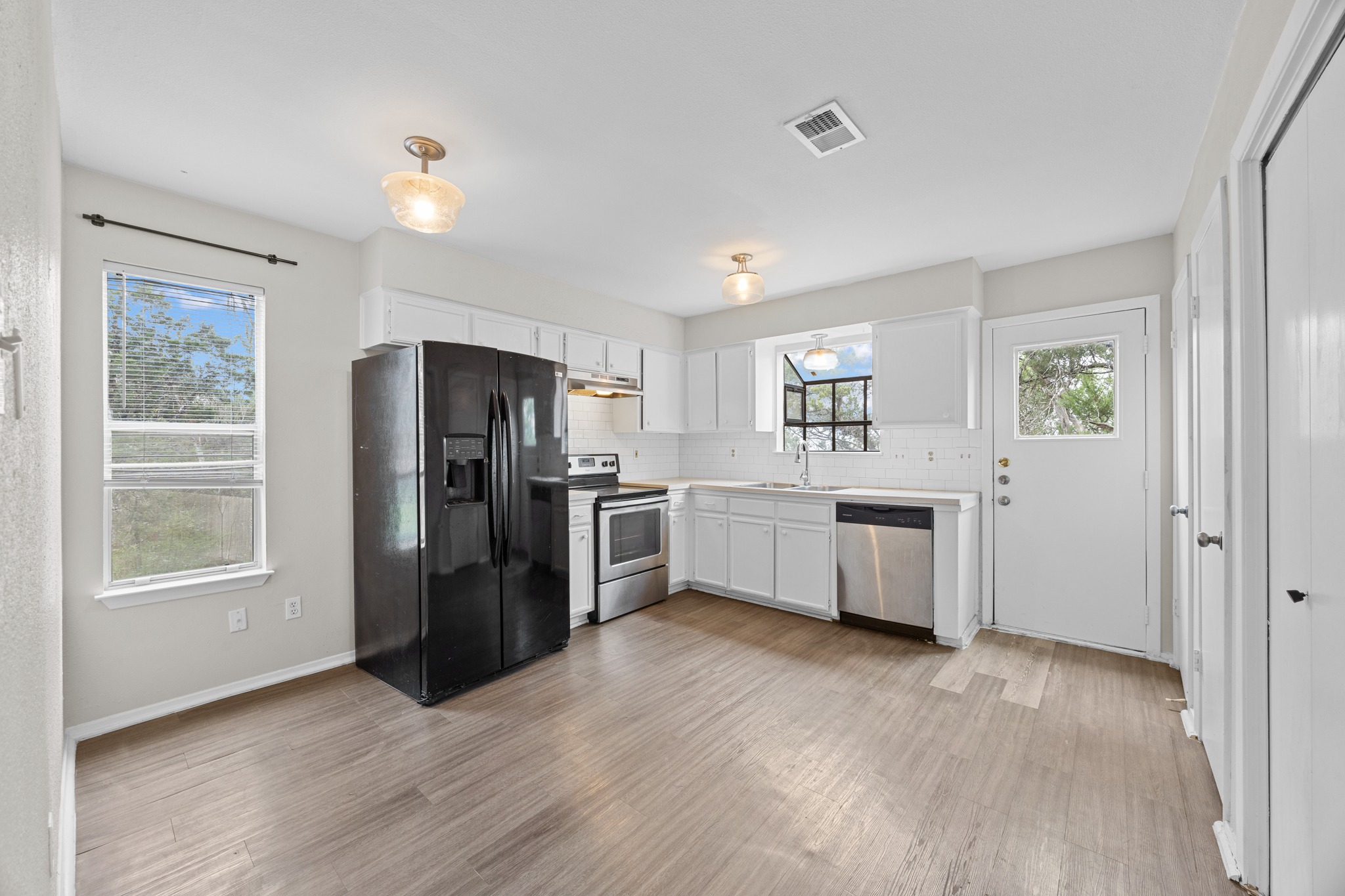 6904 Rifle Bend, Unit A Austin, TX 78736 - Photo 10 of 22 Kitchen with stainless steel appliances, white cabinets, light countertops, light wood-style flooring, and decorative backsplash