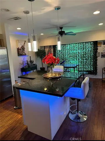 a kitchen with stainless steel appliances granite countertop a table chairs and a wooden floor