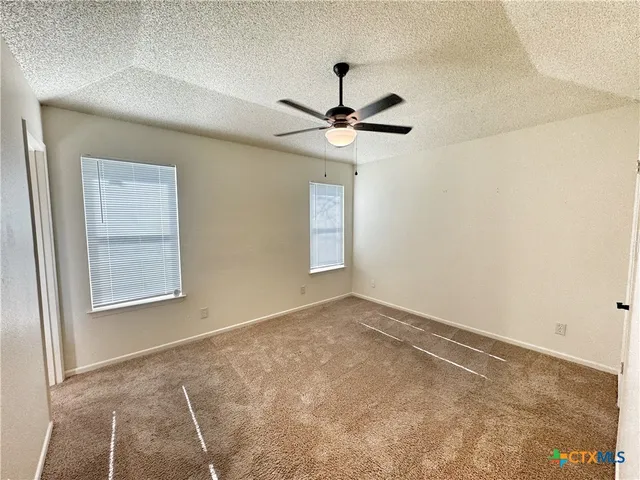 an empty room with windows and fan