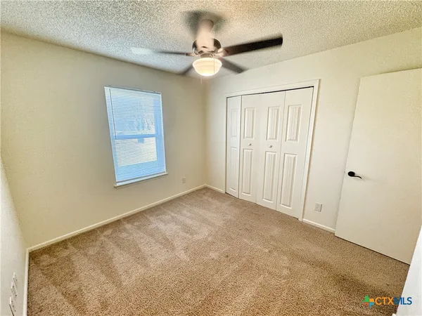 an empty room with a ceiling fan and a window