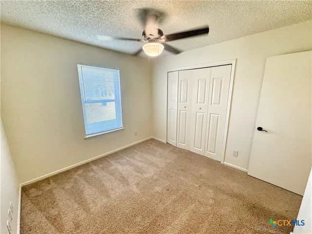 an empty room with a ceiling fan and a window