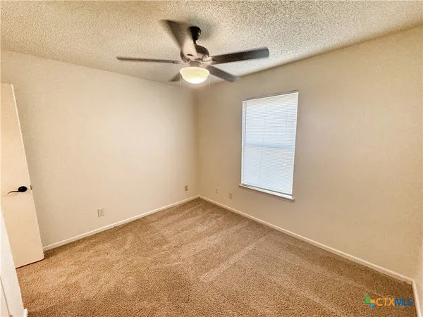 an empty room with a window and a fan
