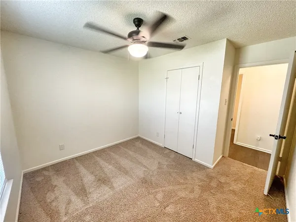 an empty room with a ceiling fan and a window