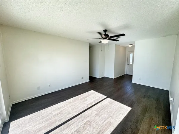 an empty room with wooden floor and a ceiling fan