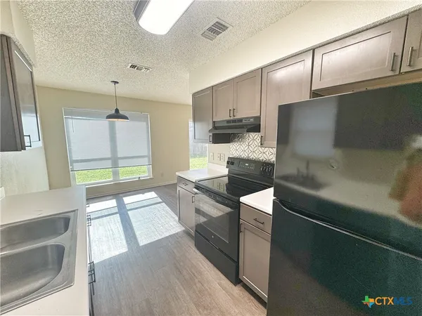 a large kitchen with a large window and stainless steel appliances