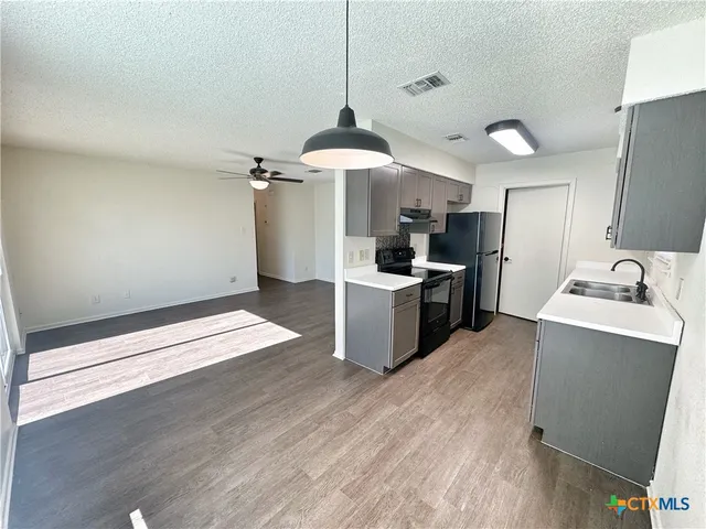 a kitchen with stainless steel appliances a sink a stove top oven a counter space and cabinets