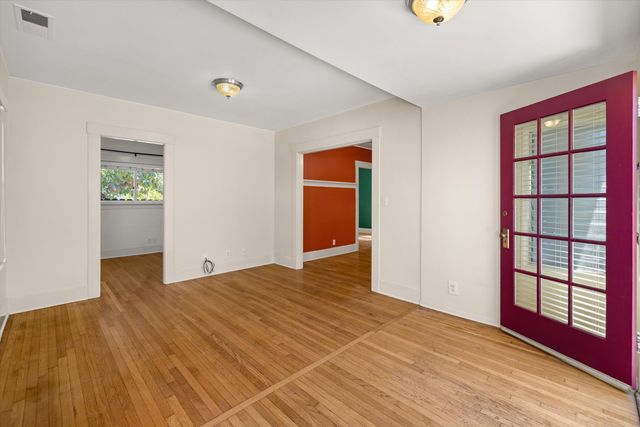 a view of an empty room with wooden floor and a window