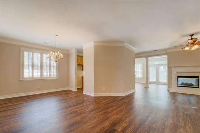 an empty room with wooden floor fireplace and windows