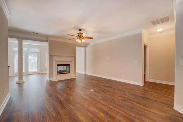 a view of an empty room with wooden floor and a fireplace