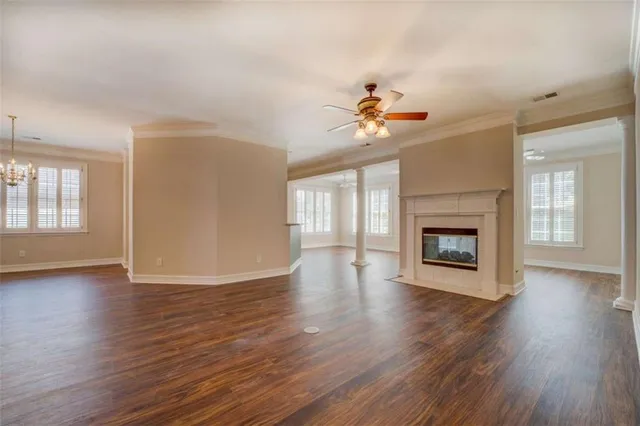 an empty room with wooden floor fireplace and windows